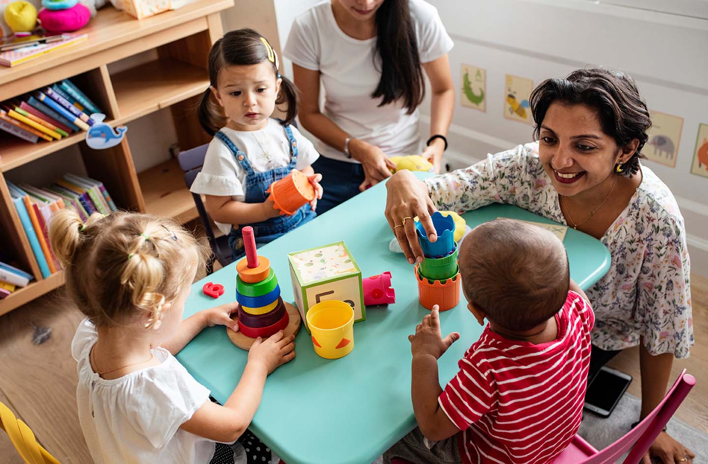 Child care teacher sitting at table with children